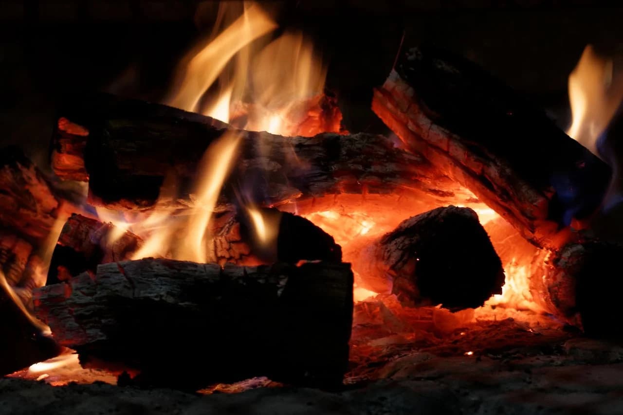Chimenea de piedra encendida en un ambiente oscuro y acogedor